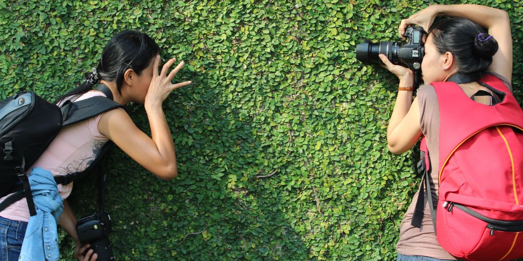 How to create a website for your club - two people lay on the grass, one photographing the other.