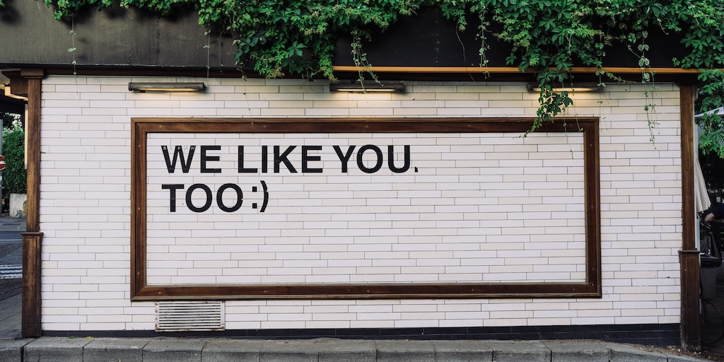 social media likes - sign says "we like you too" with a smiley face emoji