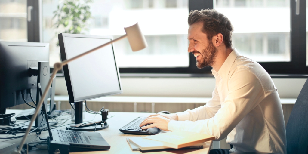 A person at a desk is smiling because they can point a domain anywhere with Hover